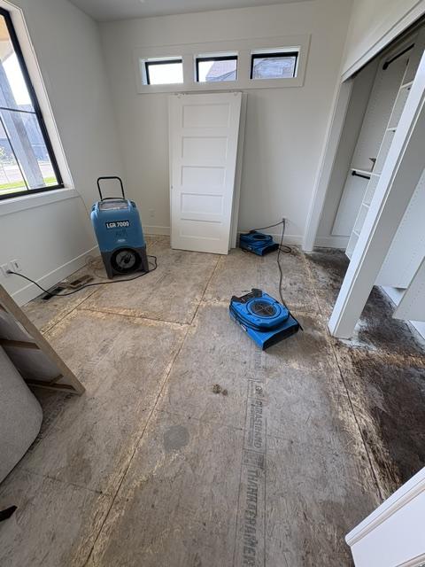 Room with exposed subfloor and drying equipment during water damage restoration